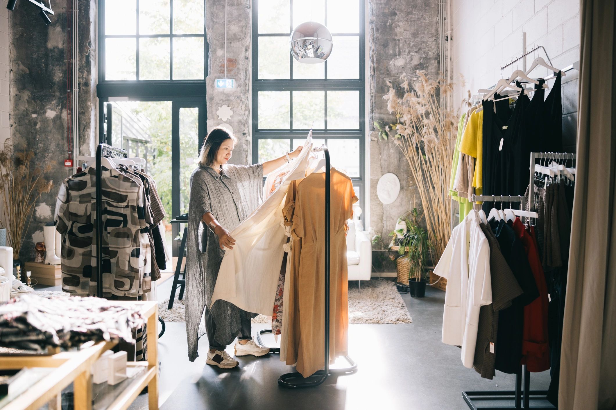 Mujer explorando una colección cuidada de vestidos en una boutique